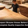Factory worker inspecting okoume veneer sheets in wood workshop, quality control for plywood raw material